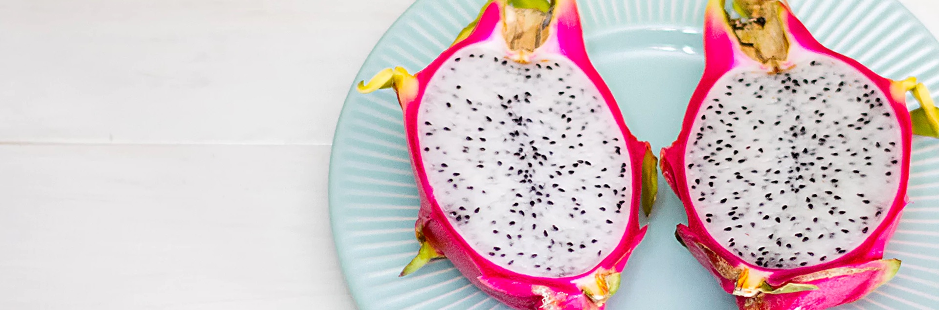 Close up of a cut dragon fruit on a teal ceramic plate
